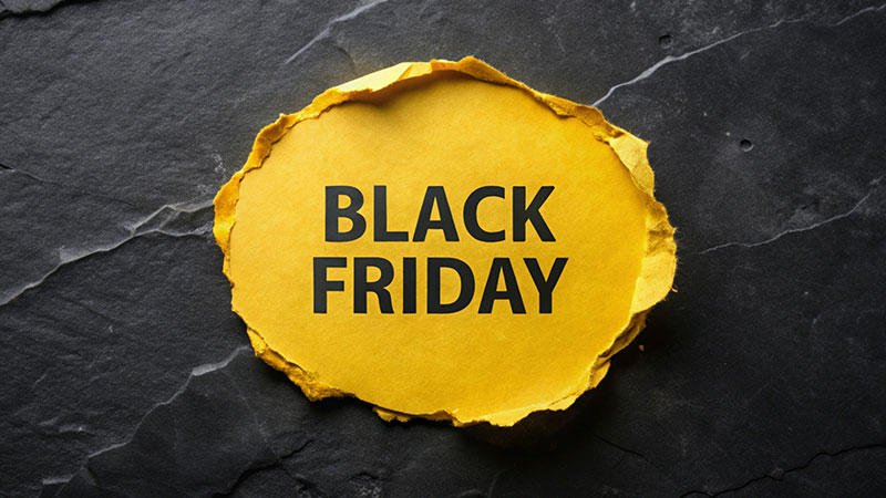 Carta gialla rotonda a strappo su sfondo nero con texture marmorizzata. Testo Black Friday su carta rotonda